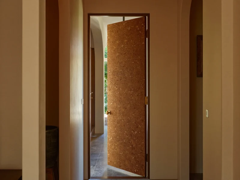 Corridoio toscano luminoso con una porta in legno massello socchiusa